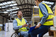 © Halfpoint - Portrait of man in wheelchair working in modern industrial factory, talking with female coworker. Concept of workers with disabilities, accessible workplace for employees with mobility impairment.