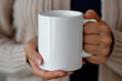 © July P - A woman's hand holds a white mug.
