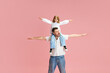 Father and daughter with arms outstretched, play airplanes pretending to fly against pink pastel background. Concept of International Day of Happiness, childhood and parenthood, positive emotions. Ad
