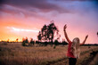 © Austockphoto - girl with long blonde hair dancing with her hands up in the air with a colourful sky