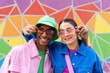© VISTA by Westend61 - Smiling couple holding sunglasses in front of colorful wall