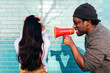 © VISTA by Westend61 - Angry man shouting through megaphone on woman with head in hands facing wall
