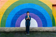 © VISTA by Westend61 - Woman using smart phone in front of rainbow wall
