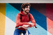 © VISTA by Westend61 - Contemplative young man on bicycle in front of colorful wall
