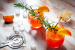 Orange drinks on a wooden background, fresh pressed juice with fruit slices, rosemary, and ice