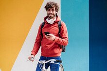 Smiling Man Standing With Bicycle In Front Of Colorful Wall