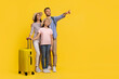 © Prostock-studio - Family Travel Concept. Happy parents with daughter carrying suitcase and pointing aside