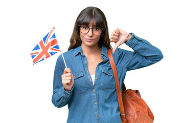 Wall Mural - Young caucasian woman holding an United Kingdom flag over isolated background showing thumb down with negative expression