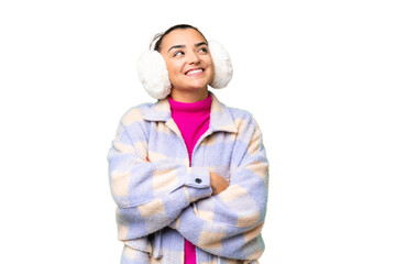 Wall Mural - Young woman wearing winter muffs over isolated chroma key background looking up while smiling