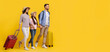 © Prostock-studio - Happy cheerful caucasian family of three walking with suitcases on yellow background
