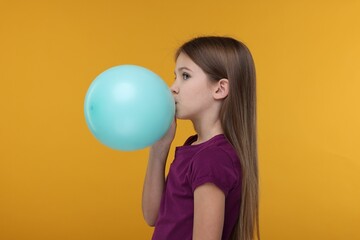 Wall Mural - Girl inflating bright balloon on orange background