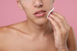 © New Africa - Man cleaning face with cotton pad on pink background, closeup
