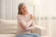 © New Africa - Mature woman suffering from pain in arm on sofa at home. Rheumatism symptom