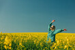 © VISTA by Westend61 - Carefree woman with arms raised standing in rapeseed field
