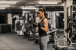 © dusanpetkovic1 - A strong sportswoman is lifting workouts with dumbbell in a gym.