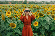 © VISTA by Westend61 - Woman looking through binoculars standing in sunflower field