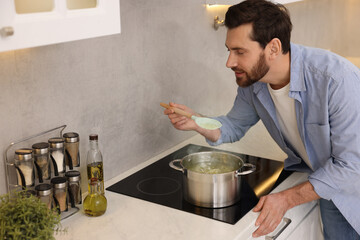 Wall Mural - Man cooking delicious chicken soup in kitchen