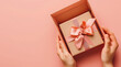 a gift box wrapped in pink ribbon lies open in a woma