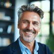 © Hasanul - Close-up headshot portrait of a mature, smiling businessman with a confident and approachable demeanor, set in an elegant office environment.