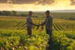 Two agriculturists in soybean field reaching an accord through a handshake.