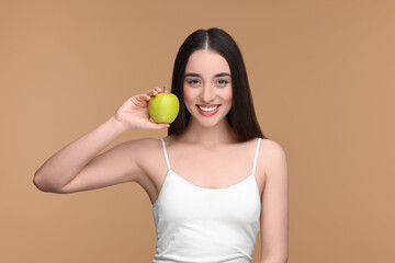 Wall Mural - Beautiful young woman with apple on beige background