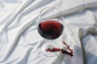 © Alexandra Selina - Glass of red wine spilled on a white tablecloth or sheet