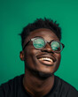 © Moritz - Confident young man with stylish glasses, smiling in casual attire on green background