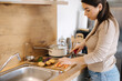 © Aleksandr - Female using knife and cutting carrot on wooden table. Home food concept
