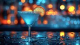 Fototapeta  -  a blue drink with a slice of orange on the rim of the drink in front of a blurry background of blurry lights and bokepted lights.