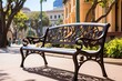 Ornate black metal bench with intricate leaf designs in a sunny urban park setting