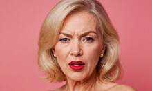 Portrait Of An Angry Sixty Year Old Blonde Woman On Isolated Pink Background. Woman With Dark Eyes And Red Lips. Beautiful Naked Evil Beauty Woman