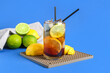 Glass of tasty Long Island iced tea and citrus fruits on color background
