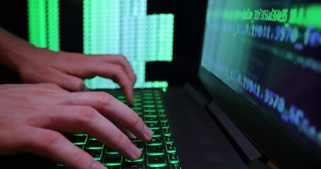 Close up of hands typing code on a laptop keyboard with multiple screens of codes and program software. Hacking or programming concept