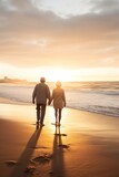 Fototapeta Natura - old senior couple walking by sea beach at sunset, older romantic man and woman walk by ocean shore at summer sunrise