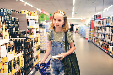 pretty girl child buying with shopping list in supermarket. beautiful female preteen kid in liquor d