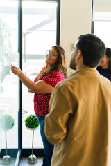 Overweight Latin woman using sticky notes on a wall and working together as a team