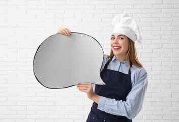 Poster - Young female chef with blank speech cloud on white brick wall background