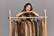 © LIGHTFIELD STUDIOS - young talented asian fashion designer looking at camera near rack with garments on grey backdrop