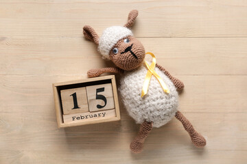 Sticker - Toy sheep with golden ribbon and calendar on light wooden background. Childhood cancer awareness concept