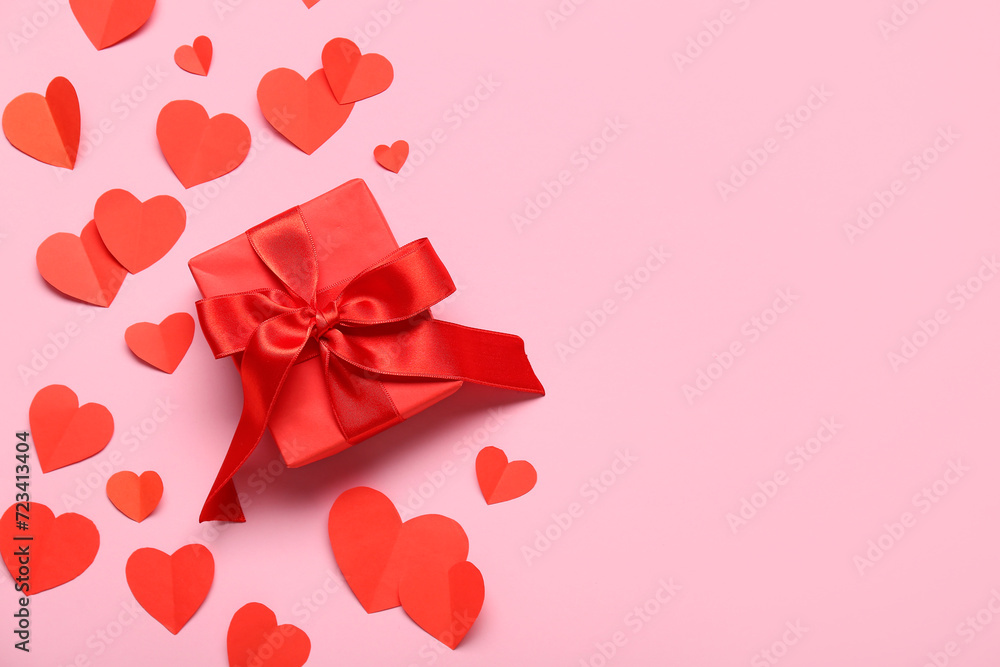 Gift box and red paper hearts on pink background. Valentine's Day celebration