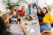 © Xavier Lorenzo - Multi generational family having fun taking photos together during dinner celebration at home