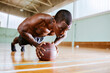 © Marko Geber - Young man doing push ups with a basketball in an indoor basketball gym