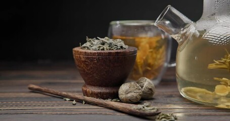 Wall Mural - Blooming flower tea ball brewing in a glass teapot with Hot boiling water on wooden background