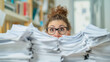 © RISHAD - Woman peeking over a mountain of paperwork.