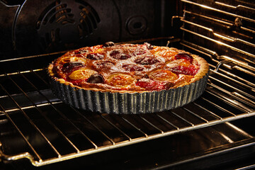 Poster - Mouth-watering image of a homemade plum pie being baked in an electric oven. The pie is filled with freshly made plum jam and exudes a delicious aroma