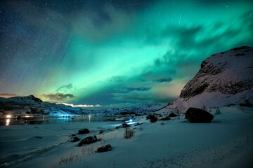 Wall Mural - aurora borealis glowing over snowy mountain on coastline in winter at lofoten islands