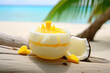 A tropical coconut milk jelly with mango pieces, served in a halved coconut shell, on a sandy beach background