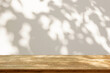 Empty wood table top on beige wall texture with tree leaves shadow background