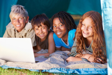 Wall Mural - Children, portrait and happy with laptop for camping in tent, social media or online movie with diversity in nature. Friends, face and group with smile outdoor on grass for trip, relax or holiday fun