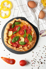 Wall Mural - Freshly baked vegetable galette with fresh vegetables on a white background